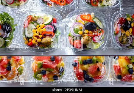 Boîtes en plastique avec salades de légumes préemballées, mises en vente dans un réfrigérateur commercial Banque D'Images
