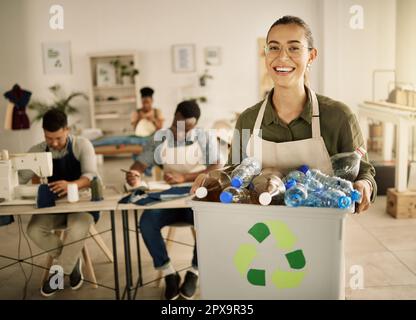 Couturière gaie tenant un seau de bouteilles en plastique recyclées. Un designer de course mixte tenant un bac de bouteilles en plastique renouvelables. Recyclage sur mesure pour jeunes Banque D'Images