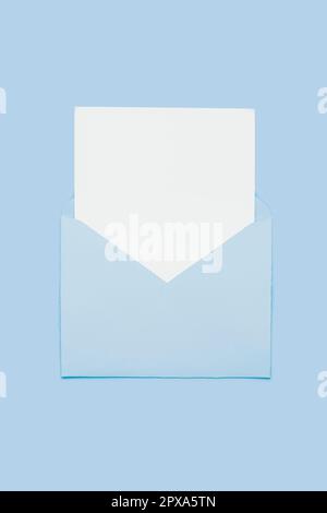 Gros plan sur une carte vierge à papier blanc dans une enveloppe bleue ouverte isolée sur un arrière-plan bleu pastel. Lettre d'amour concept minimal. Layo conceptuel Banque D'Images
