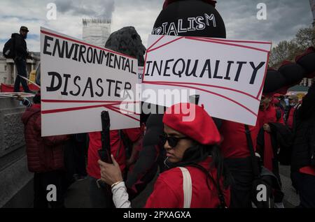 « Catastrophe environnementale » et « inégalité ». Une jeune femme, un manifestant du jour de mai, tient des signes à Trafalgar Square, Londres. 1 mai 2023. Banque D'Images