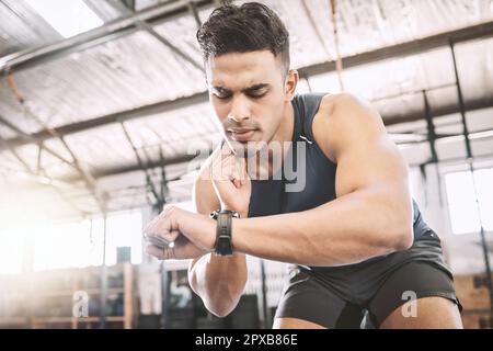 Entraînez-vous en vérifiant son pouls après un entraînement. Un jeune athlète timing ses progrès sur une montre après l'exercice. Bodybuilder traçant son battement de coeur pendant Banque D'Images