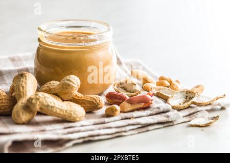 Beurre d'arachide dans un pot sur la table de cuisine. Banque D'Images