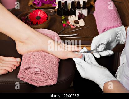 Gros plan soin des ongles par un spécialiste en pédicure dans un salon de beauté. Ciseaux professionnels pour la manucure et la pédicurie transparents pour pédicurie. Banque D'Images