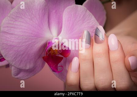 Manucure soignée pourpre sur les mains sur un fond de fleurs. Nail design Banque D'Images