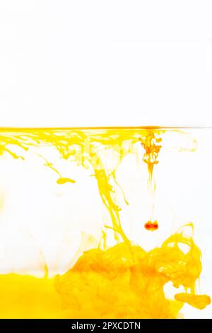 Goutte d'encre orange dans l'eau, encre orange abstraite dans l'eau sur fond blanc Banque D'Images