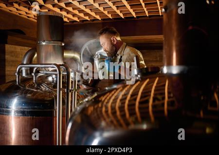 Brasseur mâle mature ajoutant de la fermentation avec de la levure ou sautez dans le réservoir à bière. Brasserie petite entreprise Banque D'Images