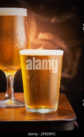 Deux verres de bière froide reposant sur une table en bois. Banque D'Images