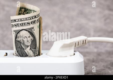 Un dollar branché dans une bande blanche d'alimentation.concept de coûts d'électricité coûteux aux États-Unis et de la hausse des prix de facture d'énergie. Banque D'Images
