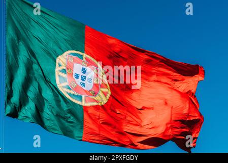 Drapeau portugais isolé sur le ciel bleu agitant dans le vent. Banque D'Images