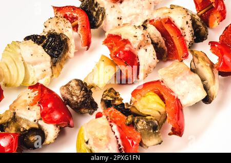 Brochettes de viande avec dinde, poivrons rouges, champignons et oignons. Proposition de repas barbecue isolée sur fond blanc. Banque D'Images