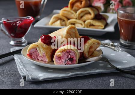 Crêpes faites maison avec garniture de caillé et cerise, servies avec une sauce à la cerise sur une assiette Banque D'Images