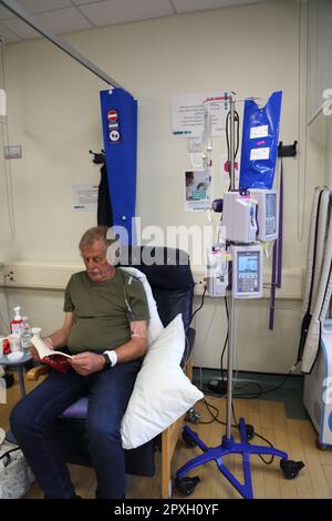 Cancer patient Reading Book tout en ayant un traitement de chimiothérapie avec perfusion intraveineuse pompe de chimiothérapie Surrey Angleterre Banque D'Images