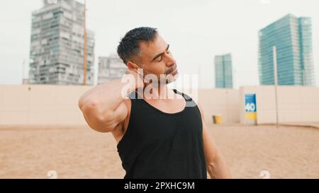 Gros plan d'un homme mature qui étire ses muscles du cou tout en se tenant sur la plage le matin Banque D'Images