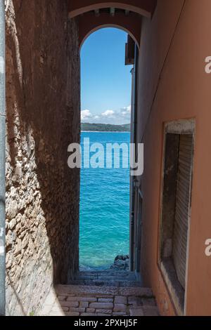 Mer Adriatique vue à travers l'étroite arche de pierre par des bâtiments dans la vieille ville médiévale de Rovinj un port de pêche par la mer Adriatique sur la péninsule Istrienne Banque D'Images