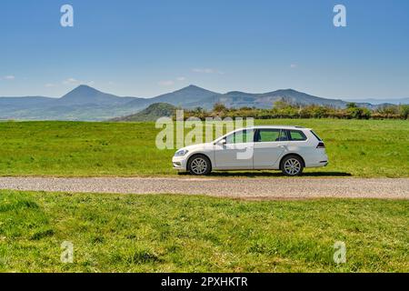 Voiture combi blanche garée dans une nature pittoresque avec vue sur les montagnes de Bohème centrale (České Středohoří: Tchèque). Réservation naturelle populaire. Banque D'Images