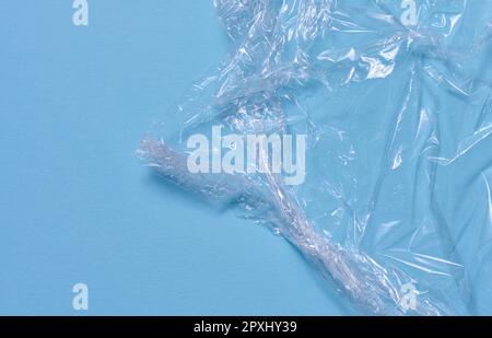 Polyéthylène transparent froissé sur fond bleu, vue de dessus Banque D'Images