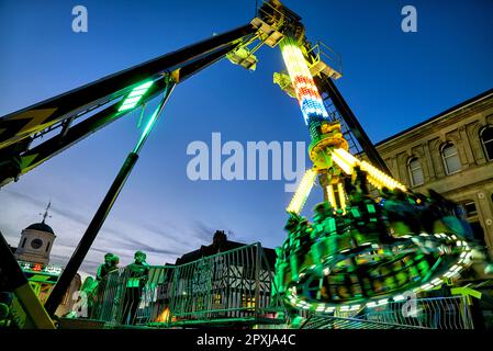 Manège de sensations fortes au parc des expositions, avec des personnes qui se sont hessées sur un bras de grue et qui se sont enroulées autour. Parcours de golf nocturne. Angleterre Royaume-Uni Banque D'Images