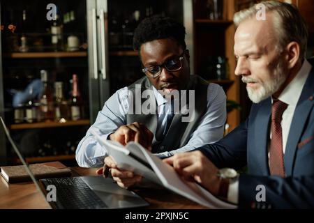 Deux partenaires d'affaires examinent le contrat assis à table pendant leur réunion au restaurant Banque D'Images