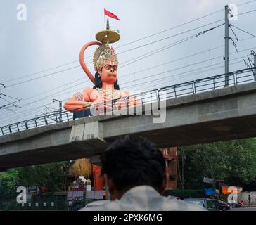 Hanuman Hindu God et temple surplombant la ligne de métro et la route principale en dessous le jour couvert dans la banlieue de Karol Bagh à Delhi, Inde. Banque D'Images