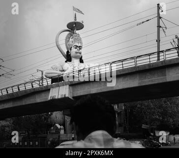 Hanuman Hindu God et temple surplombant la ligne de métro et la route principale en dessous le jour couvert dans la banlieue de Karol Bagh à Delhi, Inde. Banque D'Images