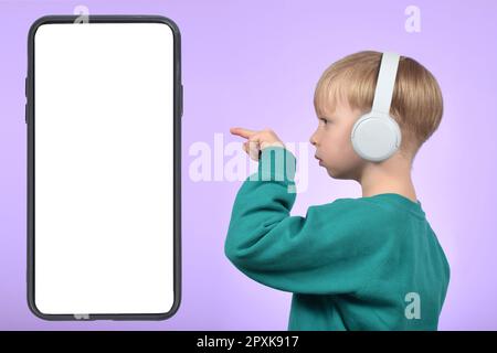 garçon enfant pointant le doigt vers le grand téléphone avec écran blanc vierge Banque D'Images