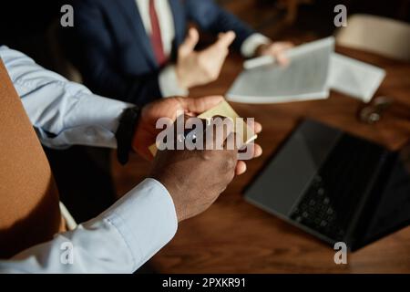 Gros plan sur le serveur afro-américain qui écrit l'ordre en note tout en servant l'homme d'affaires à table dans le café Banque D'Images