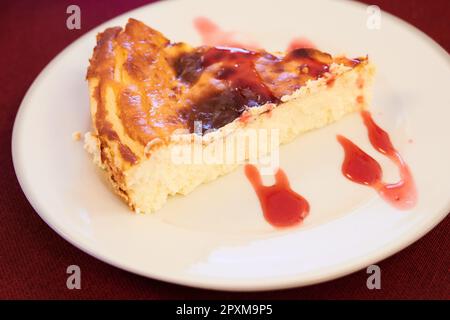 tranche de cheesecake accompagnée de confiture de fraise sur une assiette blanche Banque D'Images