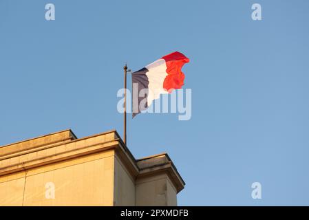 Un drapeau français vole dans le vent au coucher du soleil Banque D'Images