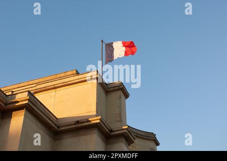 Un drapeau français vole dans le vent au coucher du soleil Banque D'Images