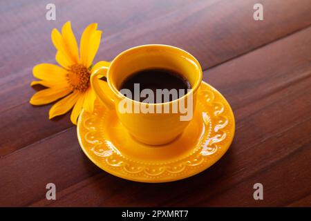 Goiania, Goias, Brésil – 01 mai 2023 : une tasse jaune avec café et un tournesol sur une table en bois. Banque D'Images