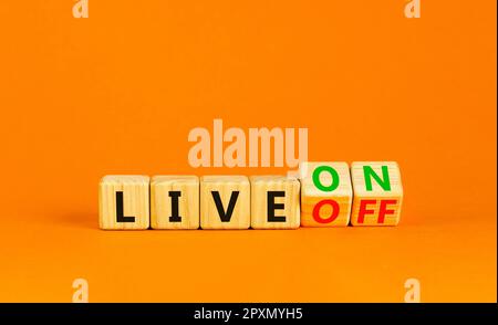 Symbole Marche ou Arrêt en direct. Homme d'affaires transforme des cubes en bois et passe de Live Off à Live On. Belle table orange fond orange. Affaires et liv Banque D'Images