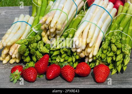 Asperges vertes, asperges blanches et fraises fraîches décorées sur une table rustique en bois Banque D'Images
