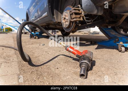 Voiture sur montage de pneu avec roue déposée sur cric pneumatique, changement de pneu saisonnier, concept d'entretien de voiture. Entretien des pneus. Changement saisonnier ou réparation de roue Banque D'Images