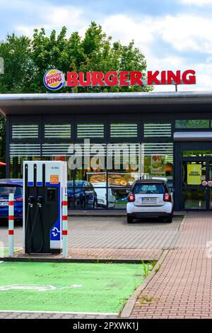 Berlin, Allemagne - 6 août 2021: Zone d'entrée d'un restaurant de restauration rapide et station de charge pour les voitures électriques dans son parking. Banque D'Images