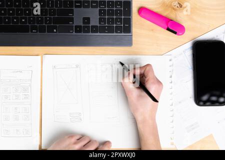 Esquisse de l'élément filaire pour le site Web. Femme designer travaillant sur une application mobile, dessin sur papier. Banque D'Images