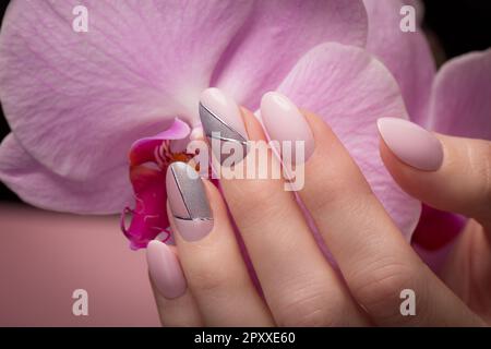 Manucure soignée pourpre sur les mains sur un fond de fleurs. Nail design Banque D'Images