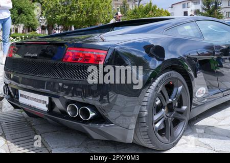 Un homme se tient devant une Lamborghini noire , en admirant la vue arrière du véhicule Banque D'Images