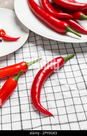 Assiettes avec piments chauds sur serviette à carreaux Banque D'Images