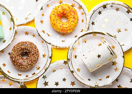 Vaisselle jetable en papier avec beignets sur fond jaune Banque D'Images