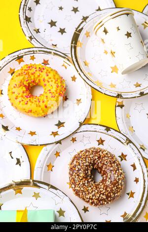 Vaisselle jetable en papier avec beignets sur fond jaune Banque D'Images