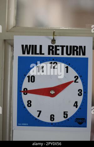 L'horloge « VA REVENIR » à la porte d'un bureau indique aux clients quand ils vont revenir. Parfois ils ne le font pas! Banque D'Images