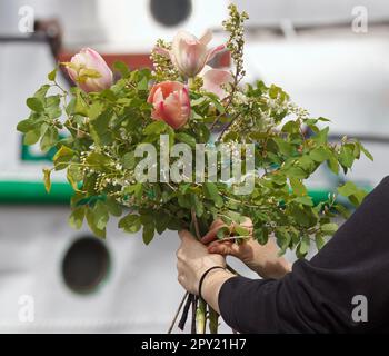 Un fleuriste lie un bouquet à un marché agricole, une main de womans tenant un grand bouquet lié. Banque D'Images