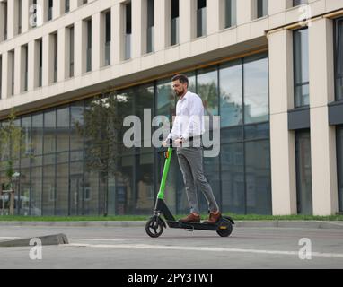 Homme d'affaires à bord d'un scooter moderne sur la rue de la ville, espace pour le texte Banque D'Images