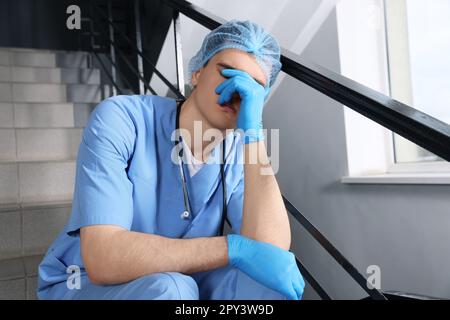 Médecin épuisé assis dans les escaliers de l'hôpital Banque D'Images
