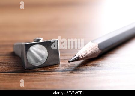 Taille-crayon en métal et crayon gris sur table en bois, gros plan Banque D'Images