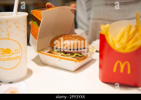 VARSOVIE, POLOGNE - 04 SEPTEMBRE 2022 : une femme avec un hamburger McDonald's, des frites et des boissons à table dans un café, en gros plan Banque D'Images