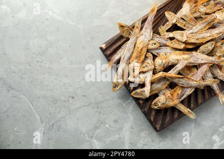 Délicieux anchois séchés sur une table en marbre gris clair, vue du dessus. Espace pour le texte Banque D'Images