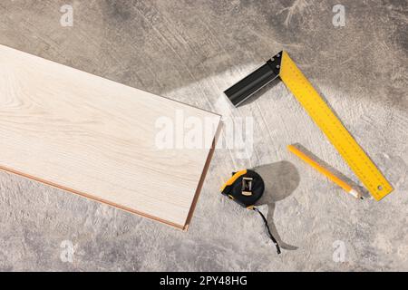 Planche de parquet, mètre ruban, crayon et règle sur le sol, plat Banque D'Images