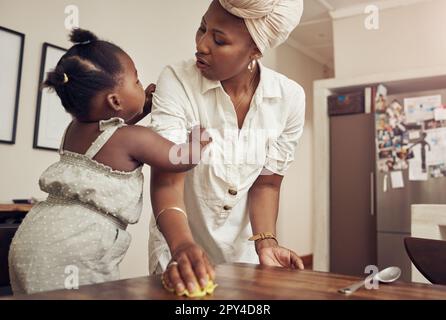 Elle veut de nouveau l'attention de mummys. une adorable petite fille se liant à sa mère pendant qu'elle nettoie à la maison. Banque D'Images