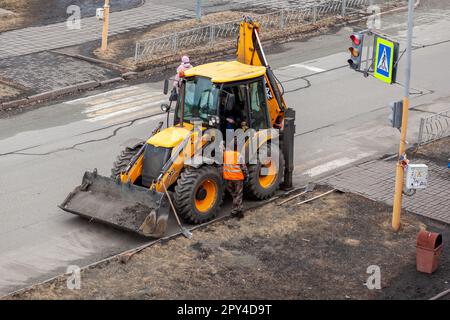 26.04.2023, Kemerovo, Russie. Un tracteur jaune est debout ou conduit sur la route pour les travaux sur route. Nettoyage de la rue avec un tracteur Banque D'Images